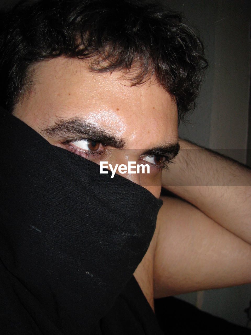 Close-up of man hiding face with black fabric