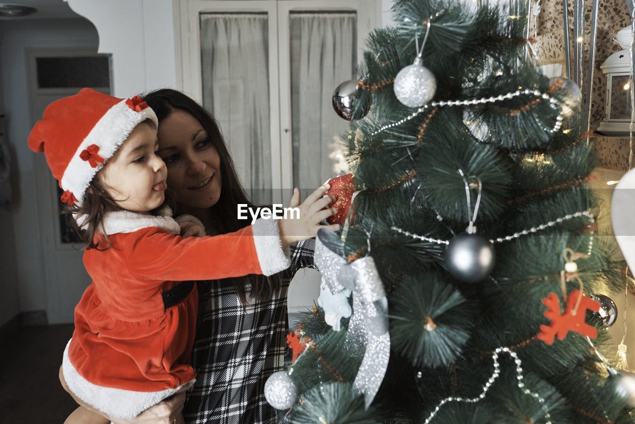 A mother and daughter decorate the christmas tree