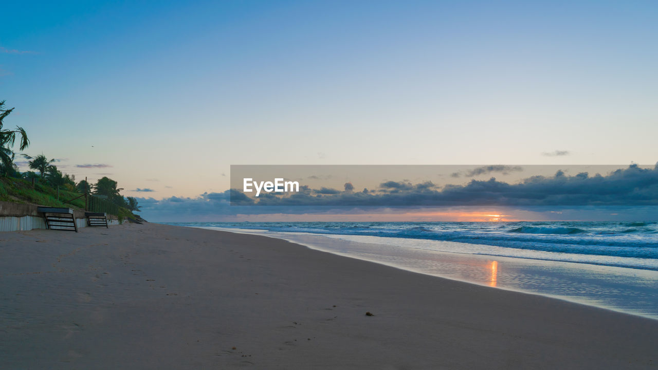 SCENIC VIEW OF BEACH AGAINST CLEAR SKY AT SUNSET