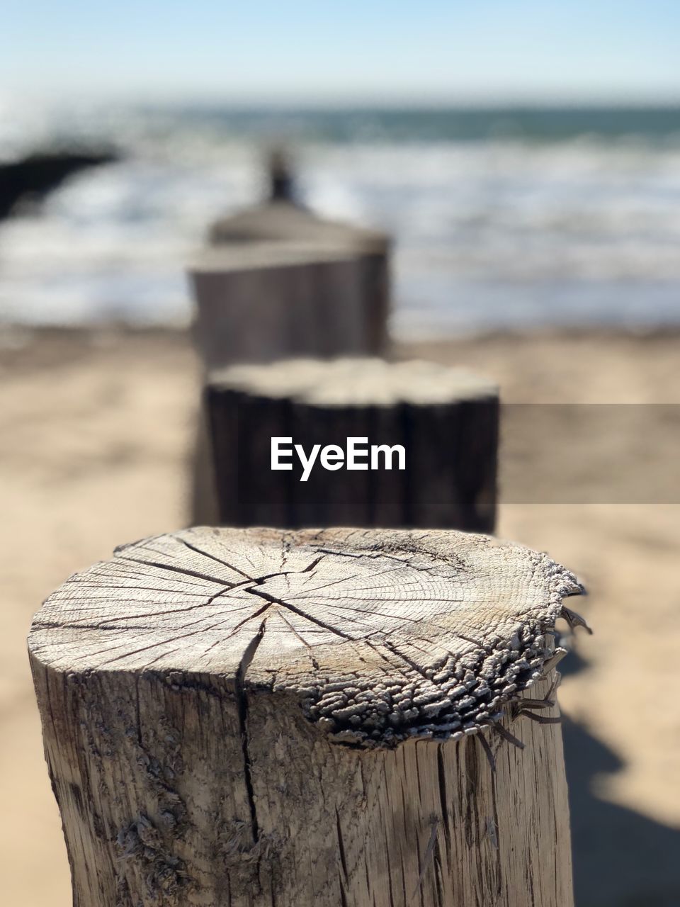 CLOSE-UP OF WOODEN POST ON SAND