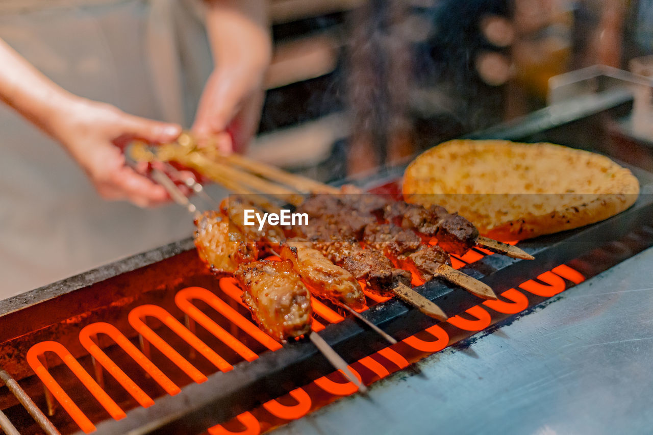 Midsection of person preparing food on barbecue grill