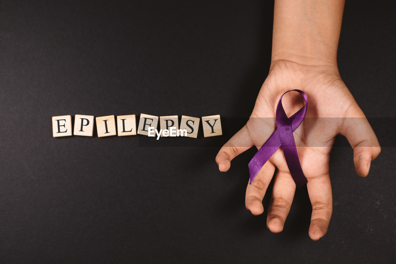 Cropped hands holding ribbon against black background