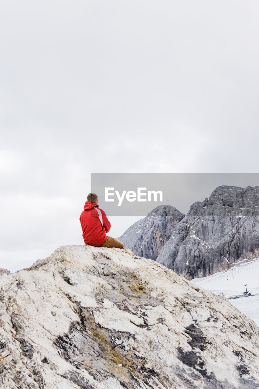 Young millennial man enjoys the views of the alps standing on glacier