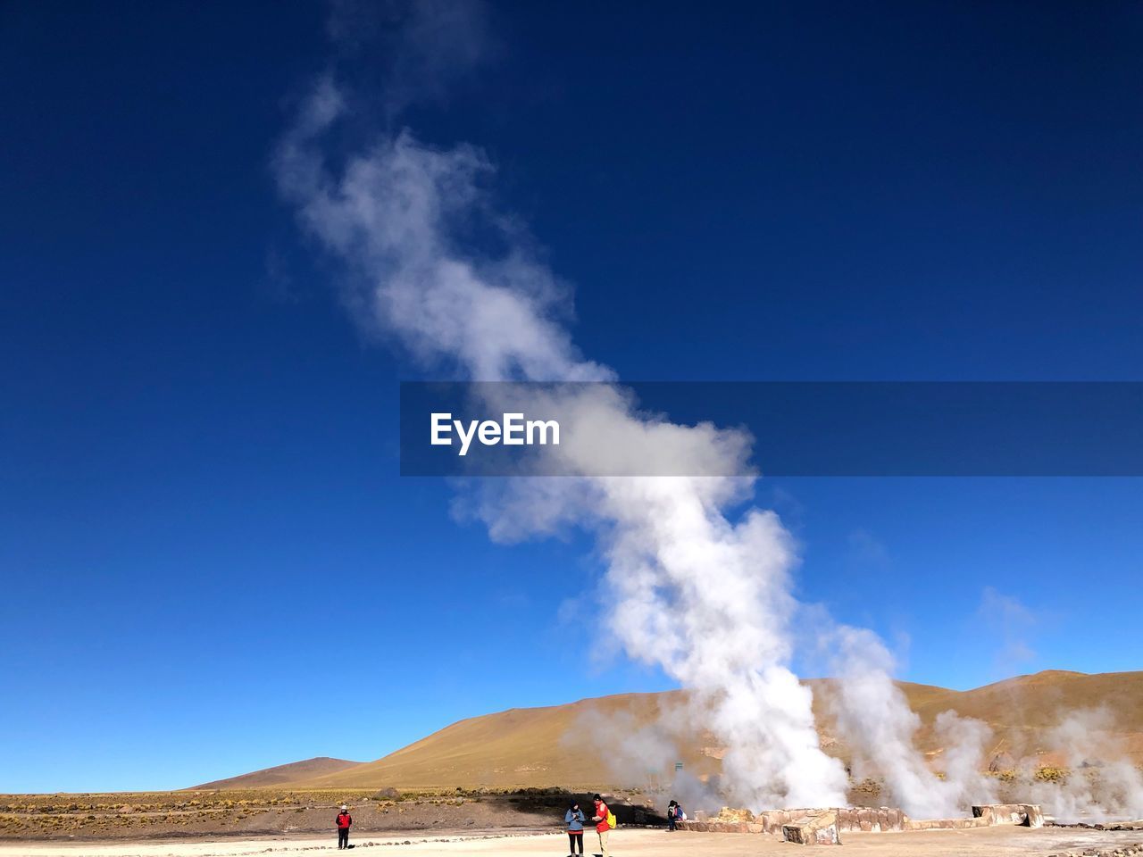 PANORAMIC VIEW OF SMOKE EMITTING FROM LAND AGAINST BLUE SKY