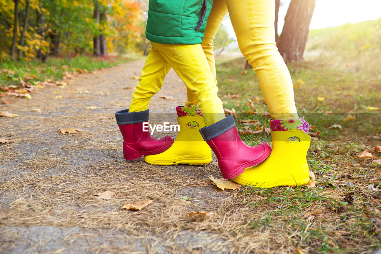 LOW SECTION OF WOMAN WEARING YELLOW SHOES ON GROUND