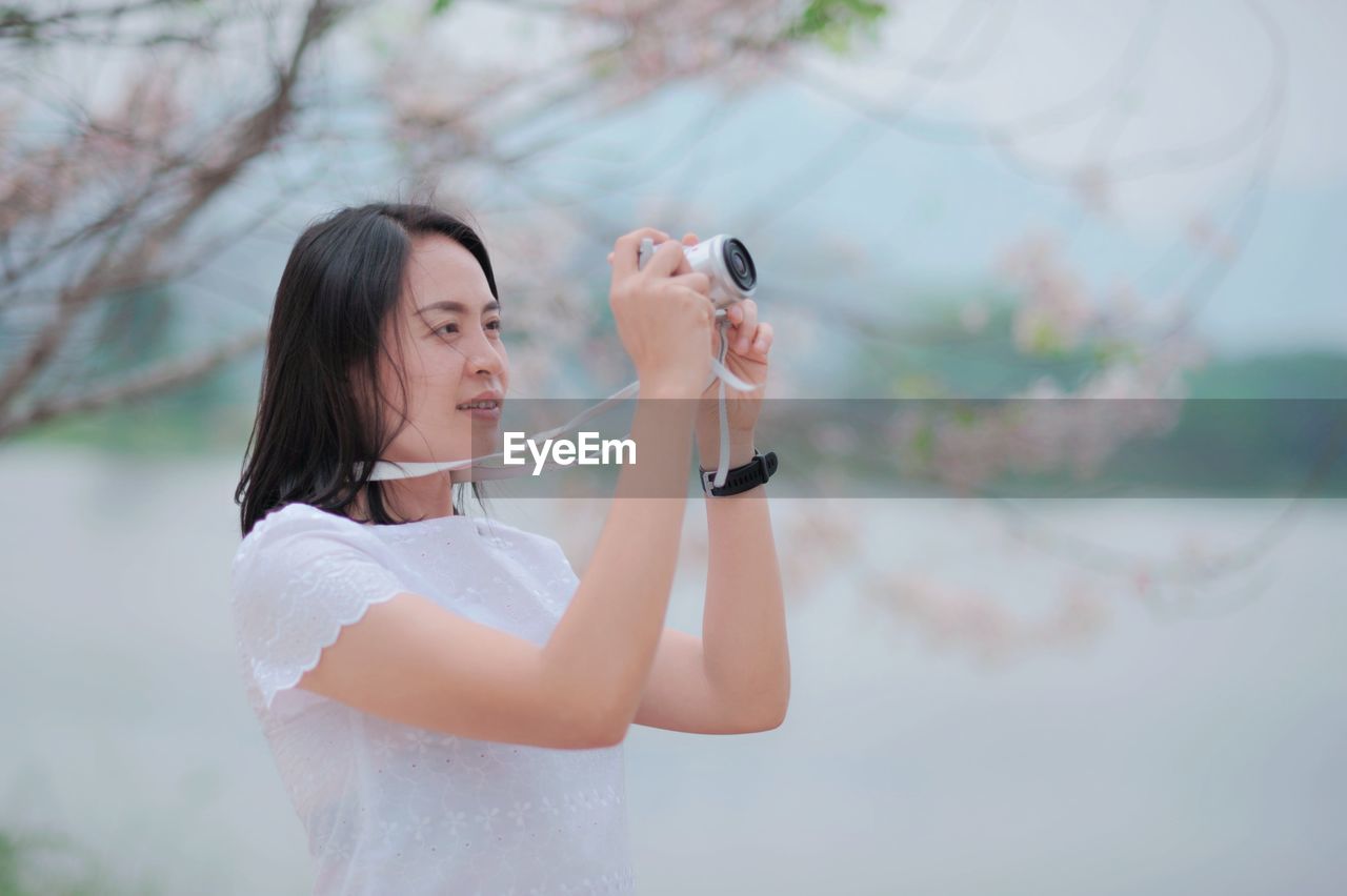 YOUNG WOMAN PHOTOGRAPHING WITH MOBILE PHONE