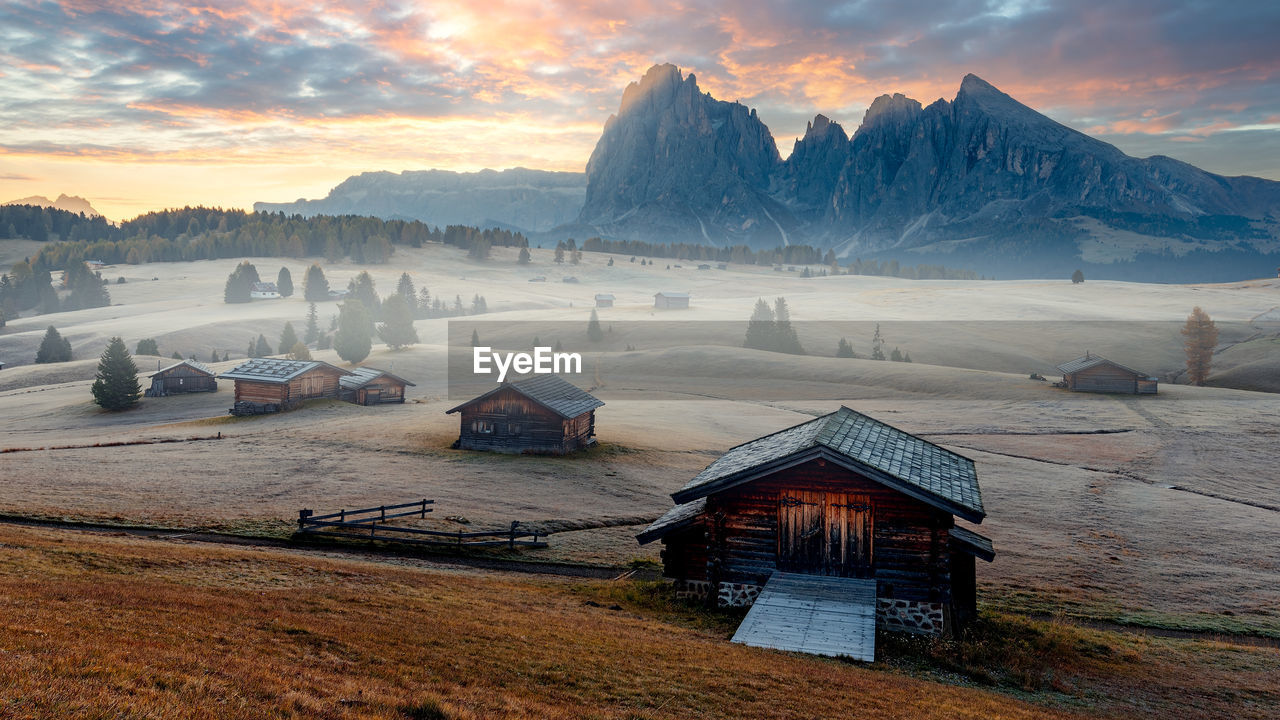 House on snowcapped mountains against sky during sunset