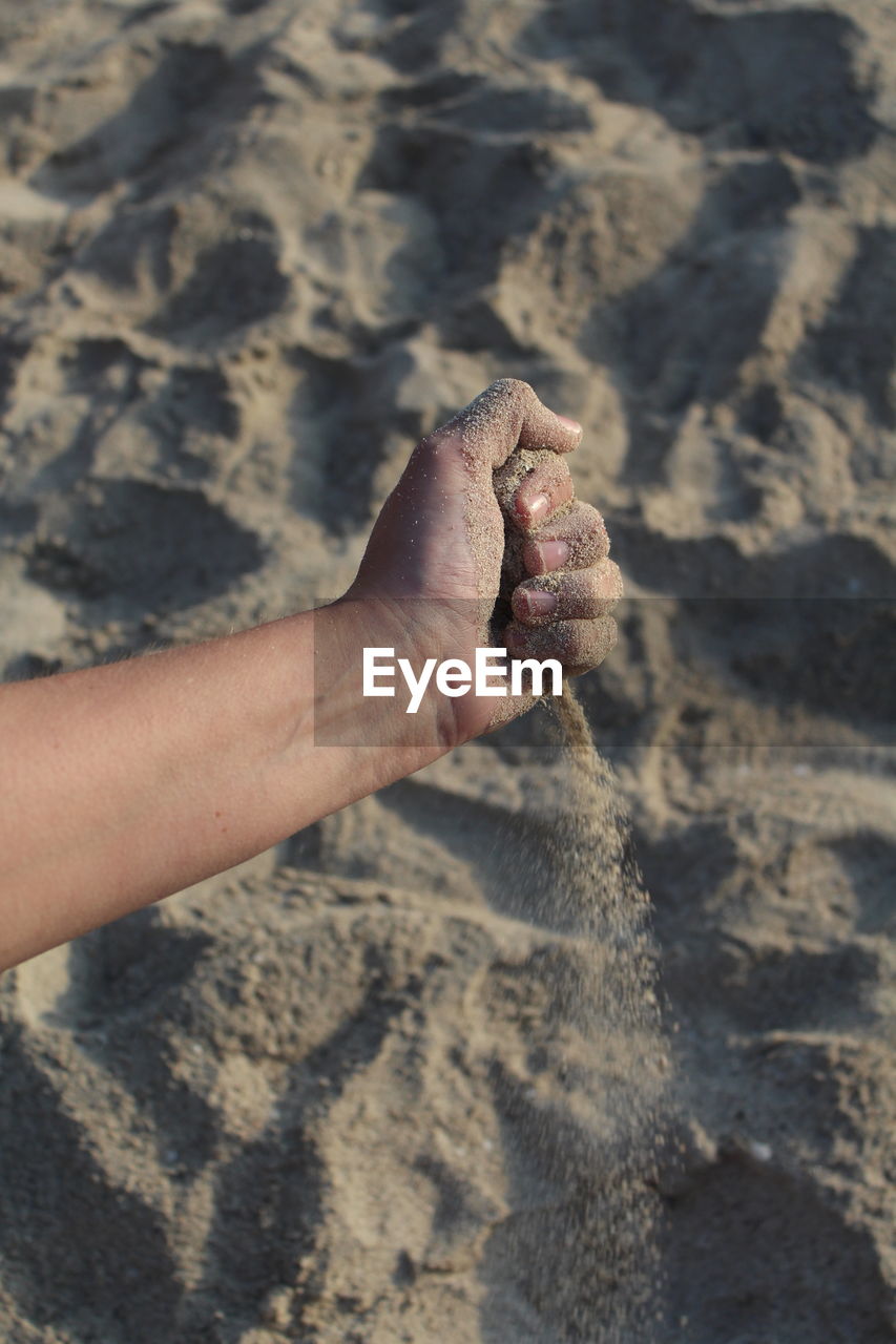 CLOSE-UP OF PERSON HAND ON SAND