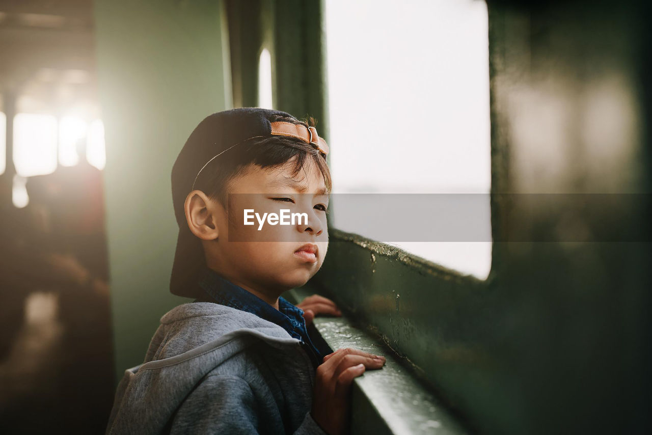 Boy looking away through window in train