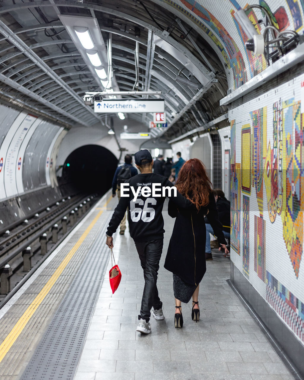 REAR VIEW OF PEOPLE STANDING ON RAILROAD STATION PLATFORM