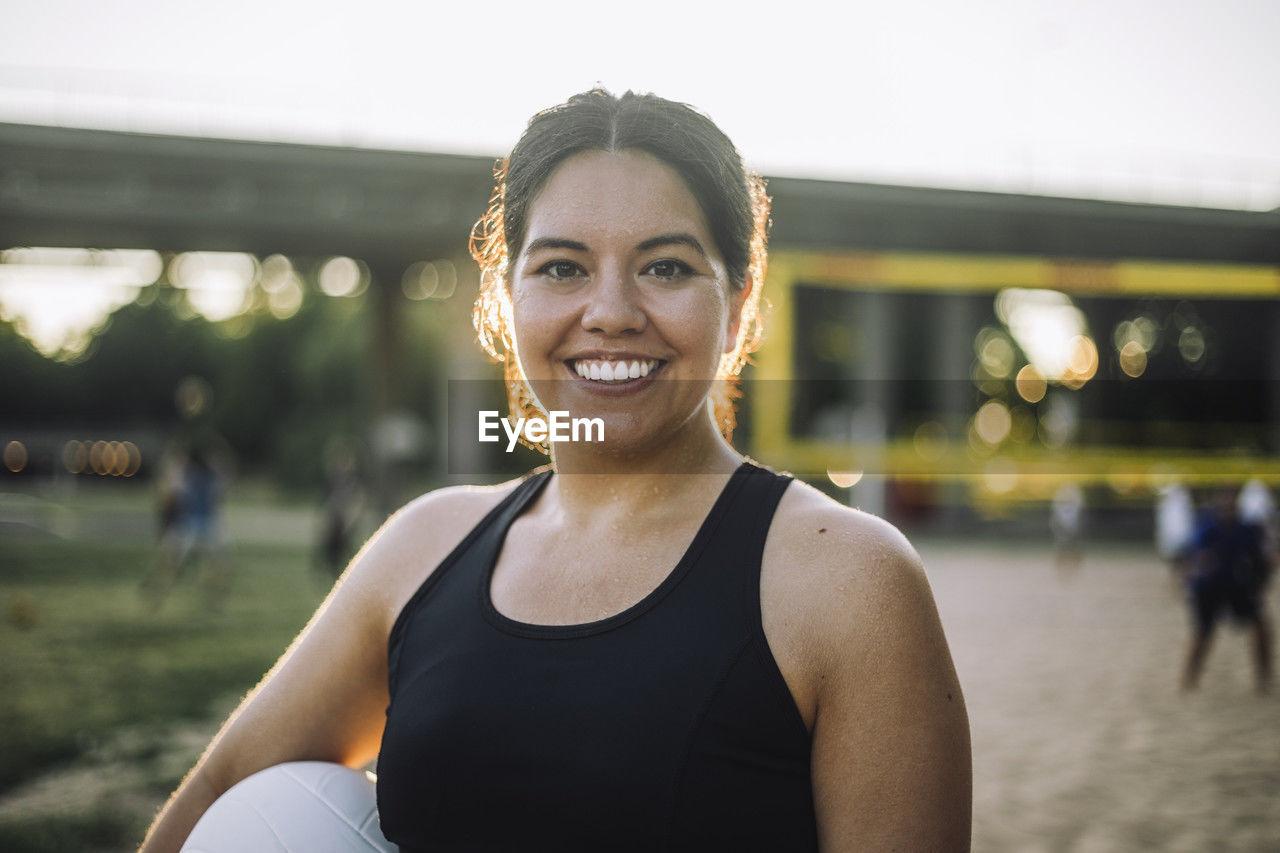 Portrait of smiling woman holding volleyball