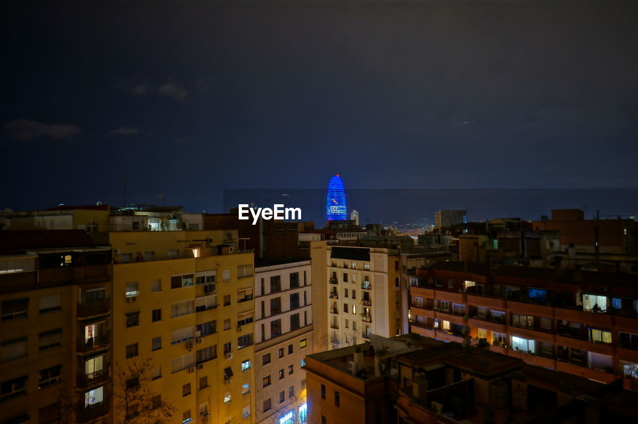 ILLUMINATED BUILDINGS IN CITY AGAINST SKY AT NIGHT