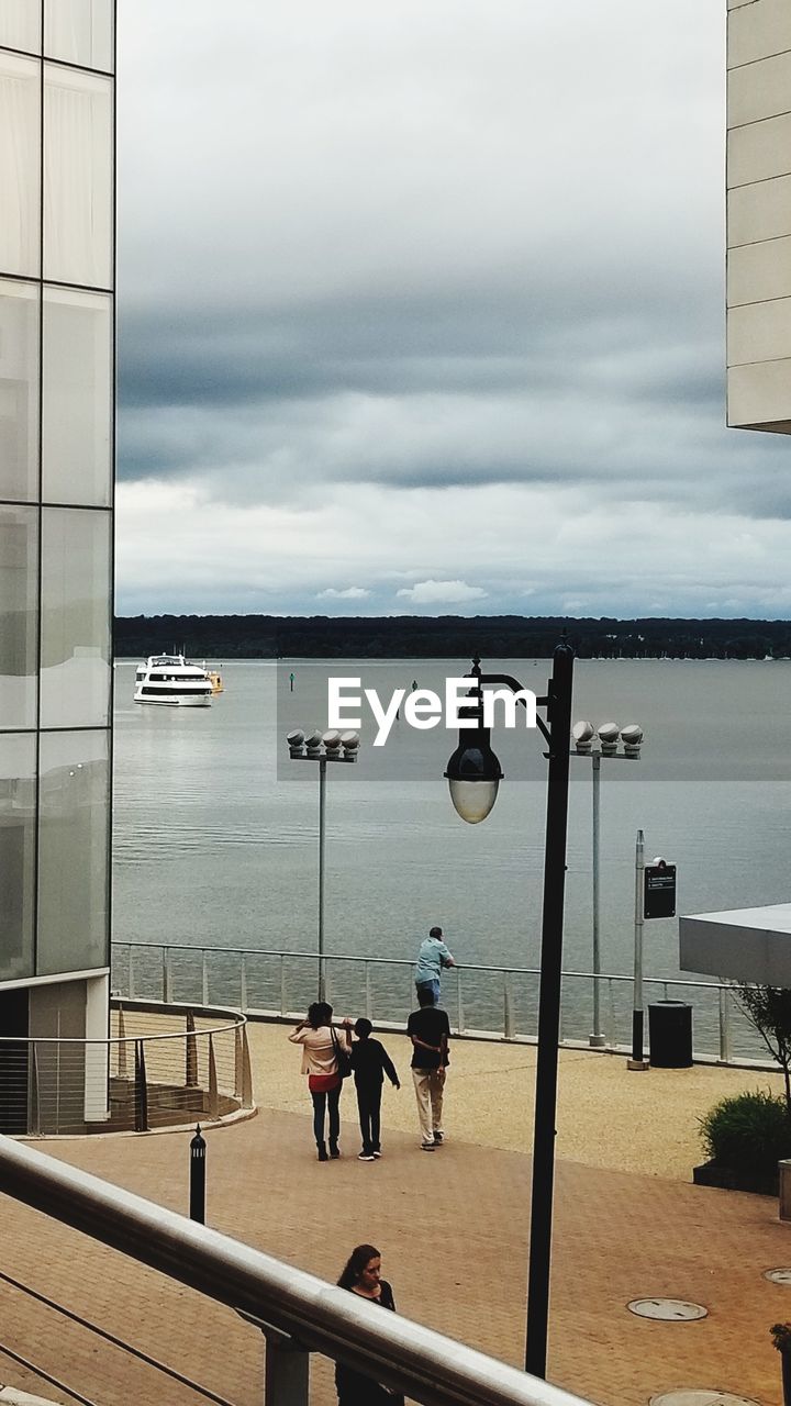 REAR VIEW OF PEOPLE OVERLOOKING CALM SEA