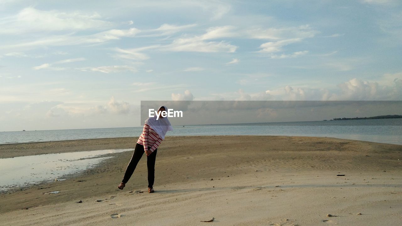 Woman standing at beach against sky