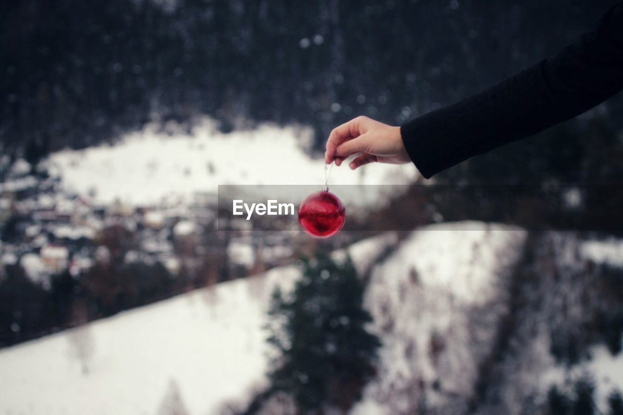 Cropped hand holding red bauble during winter