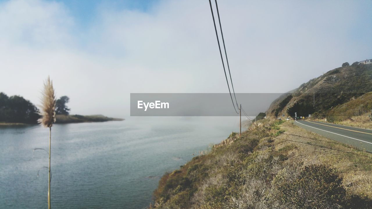 Scenic view of fog over river and land  against sky