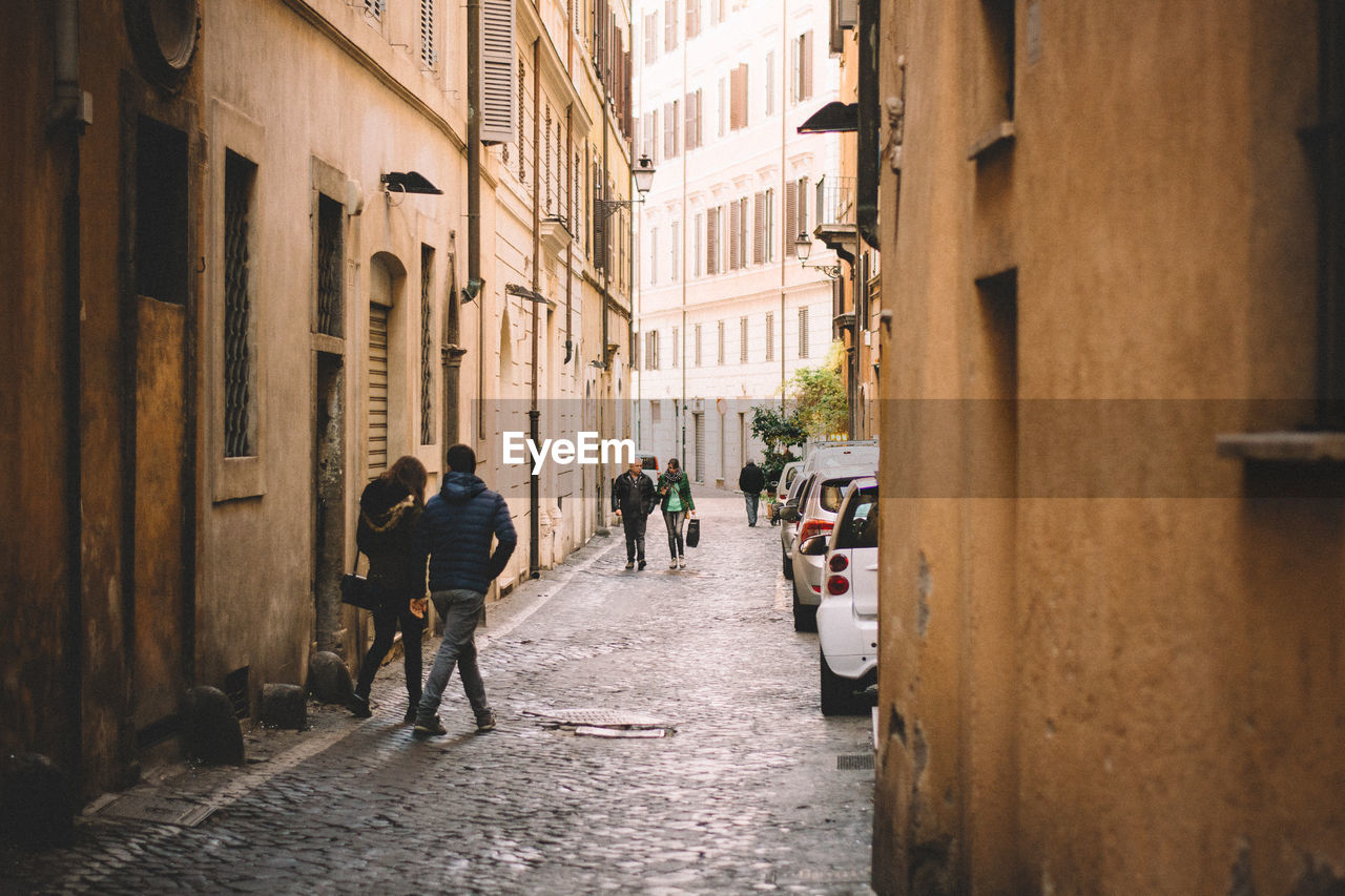 People walking on alley amidst buildings in city