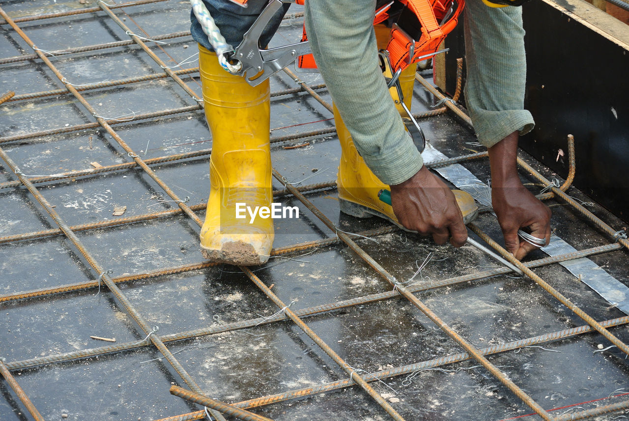Low section of man working on metal fence