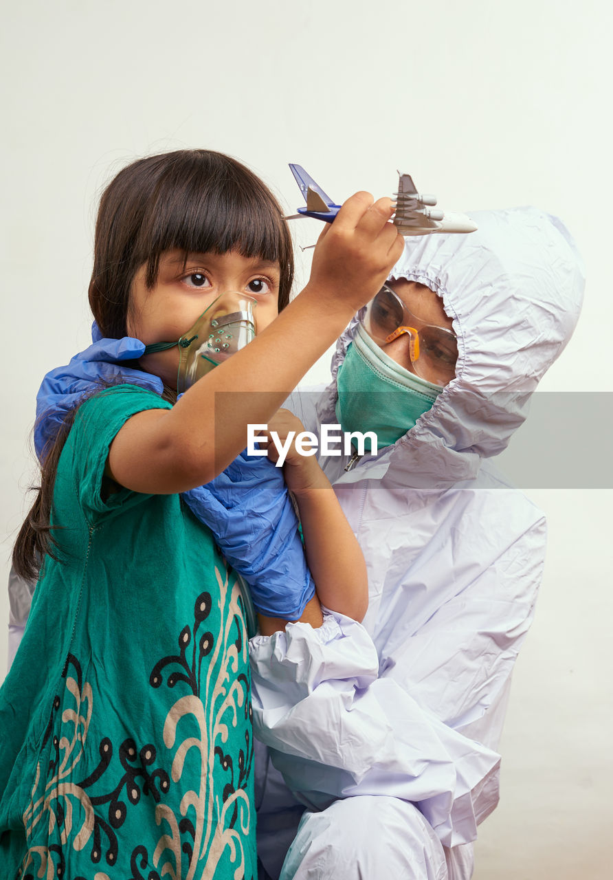 Doctor with girl wearing mask against white background