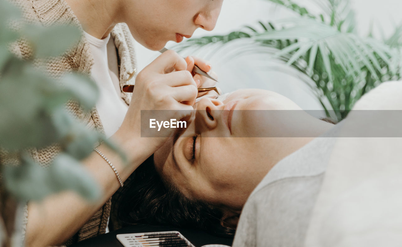 Portrait of a girl cosmetologist extending eyelashes to a woman.