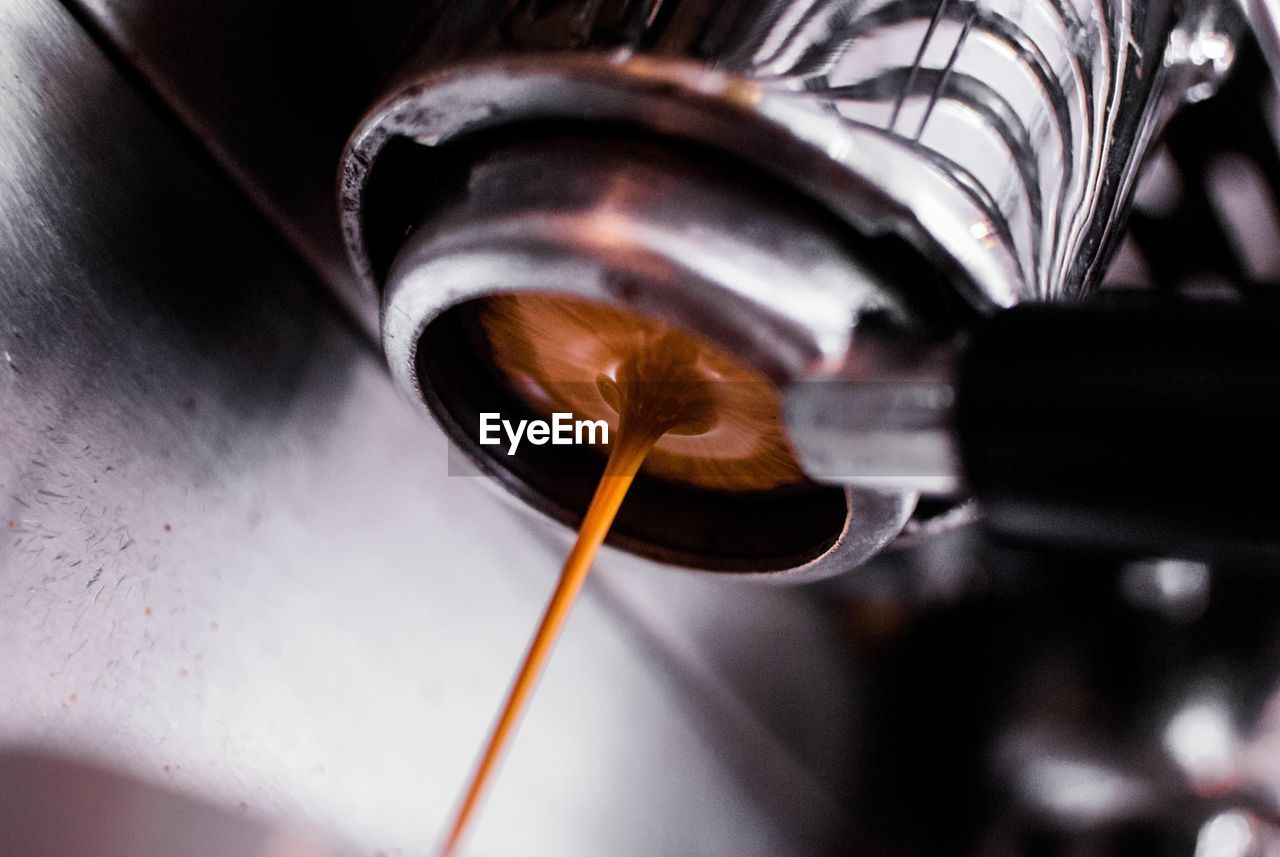 Close-up of coffee dripping from machinery