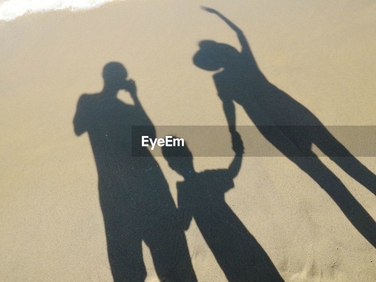 Shadow of family at beach during sunny day