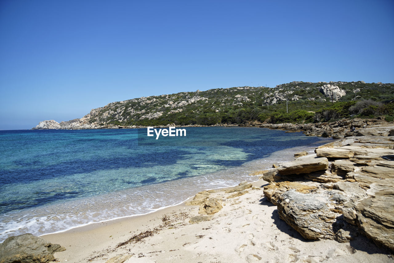 ROCKS ON BEACH AGAINST CLEAR BLUE SKY