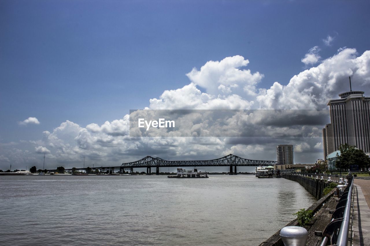 Bridge at distance against clouds with waterfront