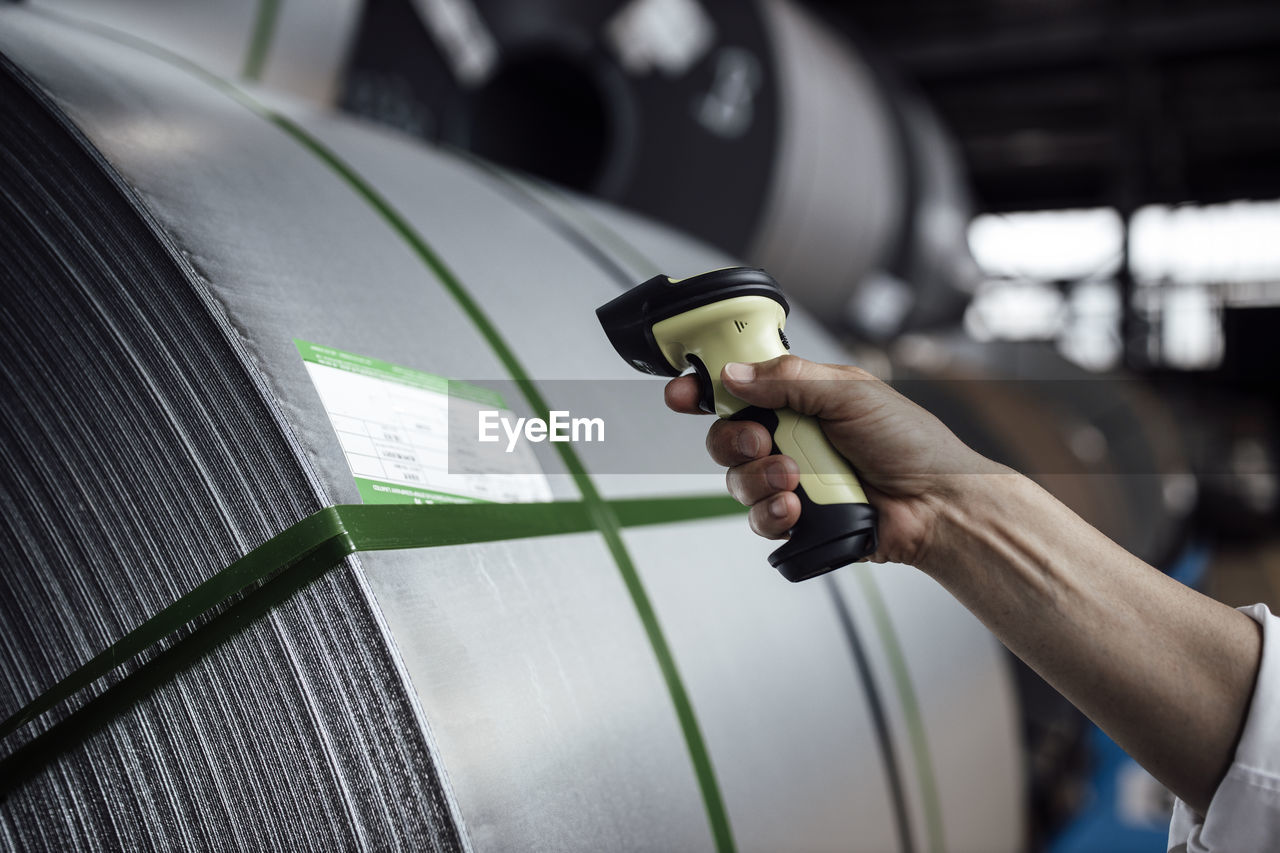 Man's hand scanning barcode on steel rolls in industry