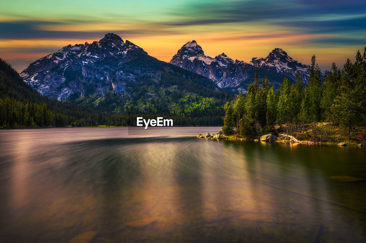 scenic view of lake by snowcapped mountains against sky during sunset