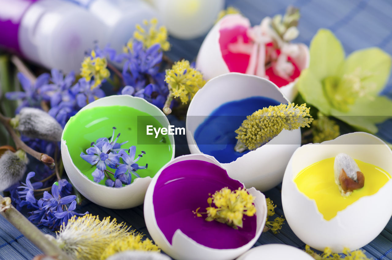 Close-up of eggshell with flowers and paint tubes on table