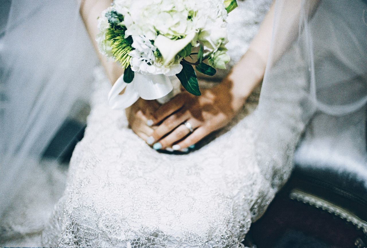 Midsection of bride holding flower bouquet