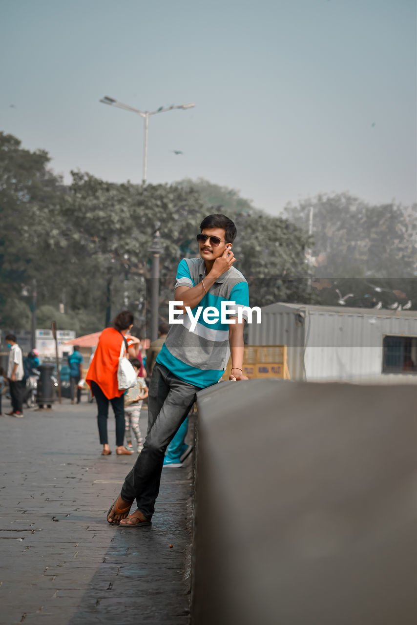 Young guy standing in city against sky