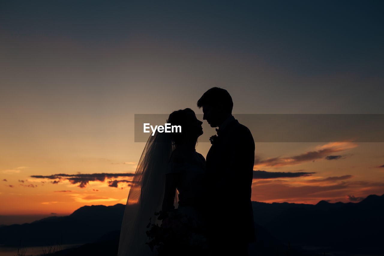 SILHOUETTE COUPLE ON ORANGE SUNSET SKY