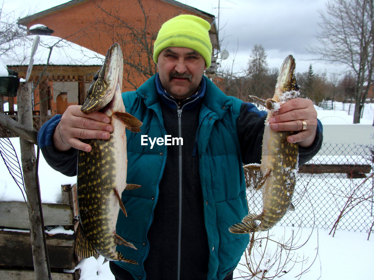 Happy fisherman with two pike in his hands