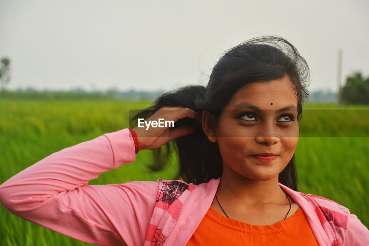 Portrait of beautiful woman standing on field