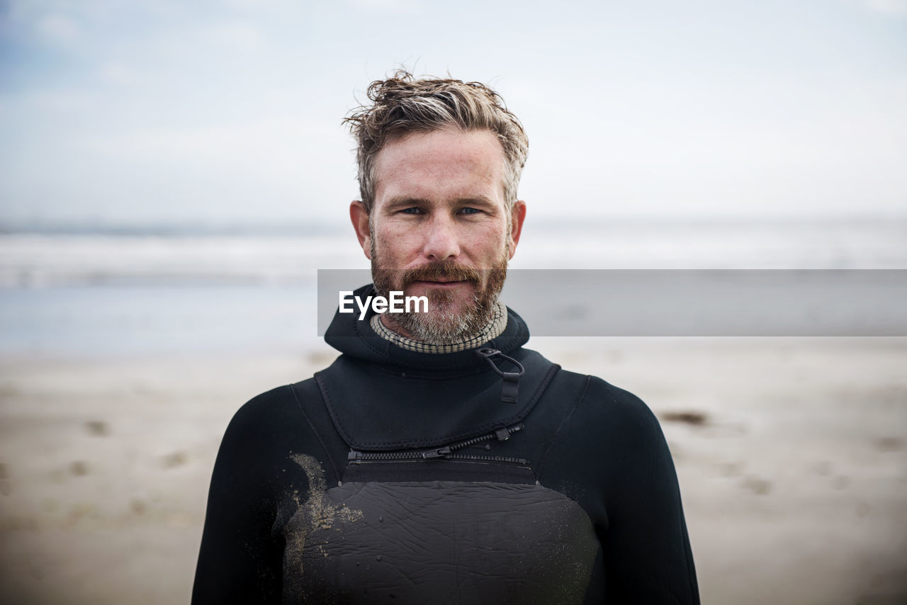 Portrait of confident surfer standing at beach