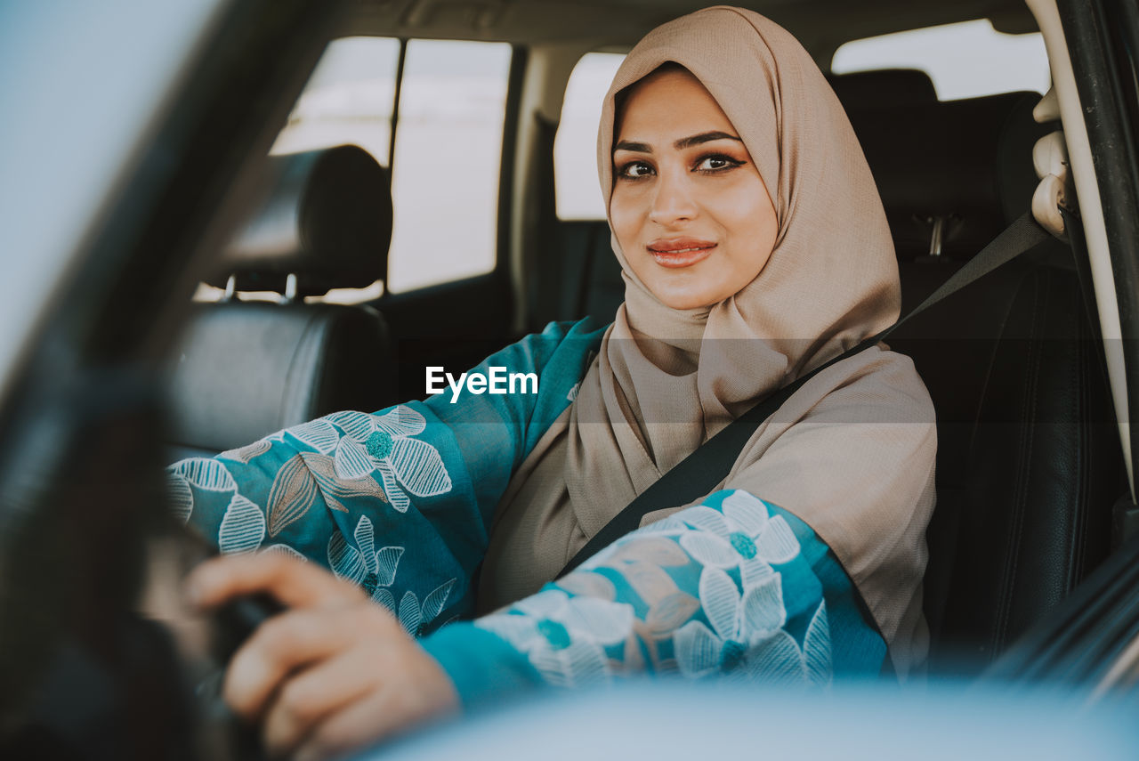 Portrait of smiling woman in hijab sitting in car