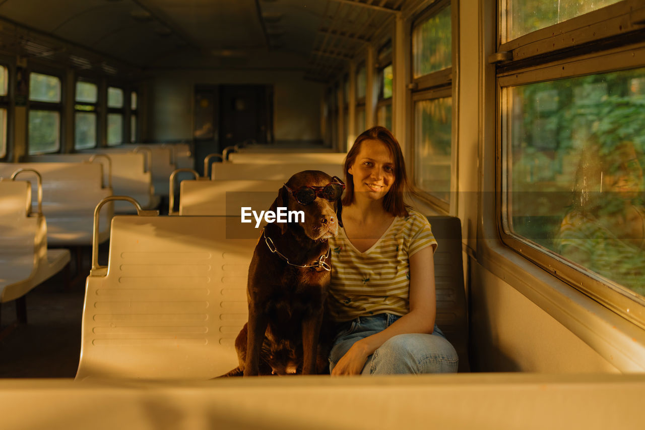Woman and retriever dog ride a train, look out the window. traveling with a pet on public transport