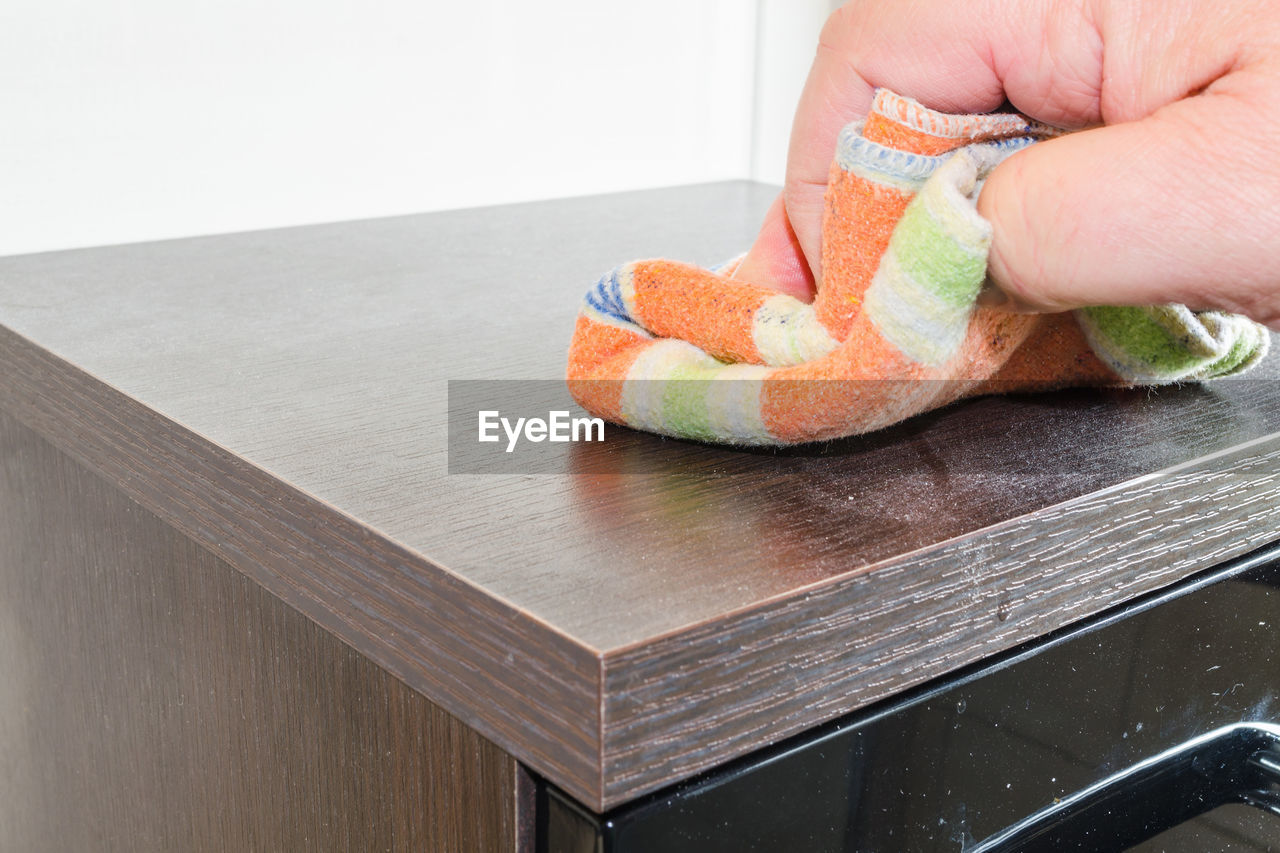 Cropped hand cleaning wooden table with duster