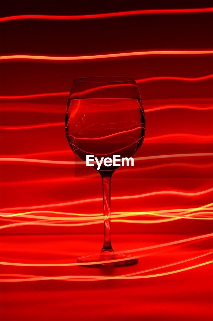 Close-up of wine glass against red abstract