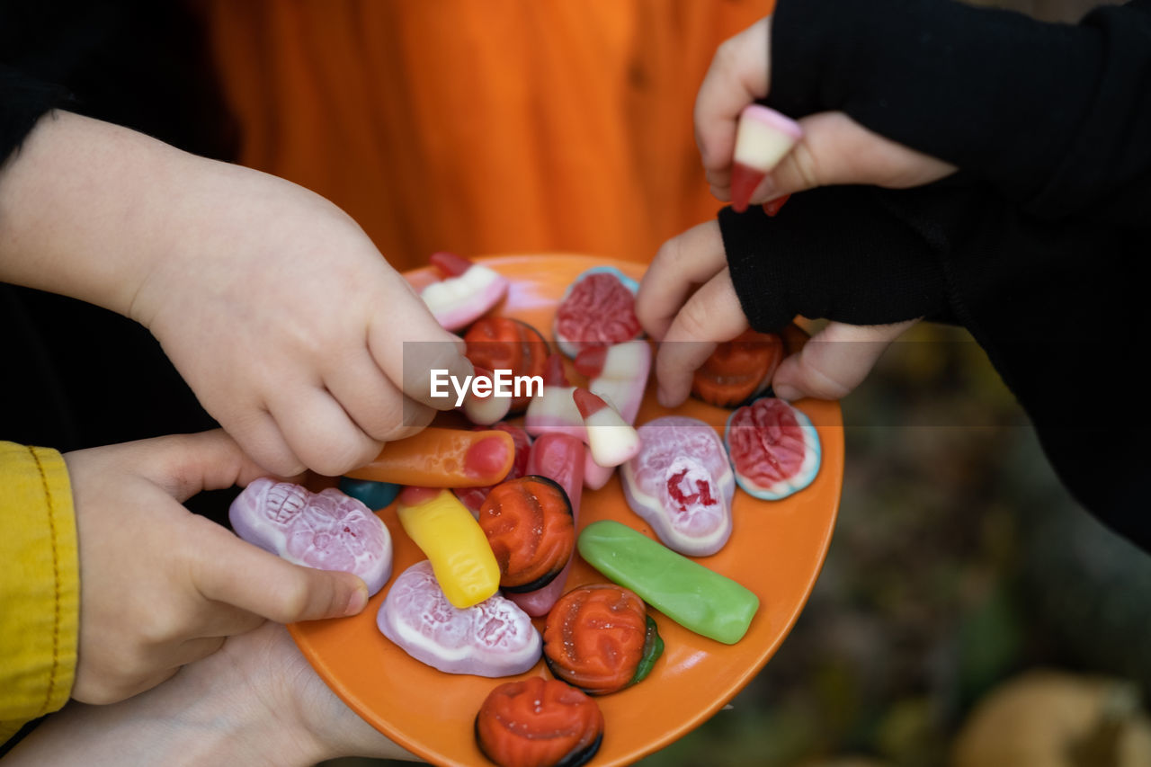 Halloween background. children's hands reach for the scary candy on the plate