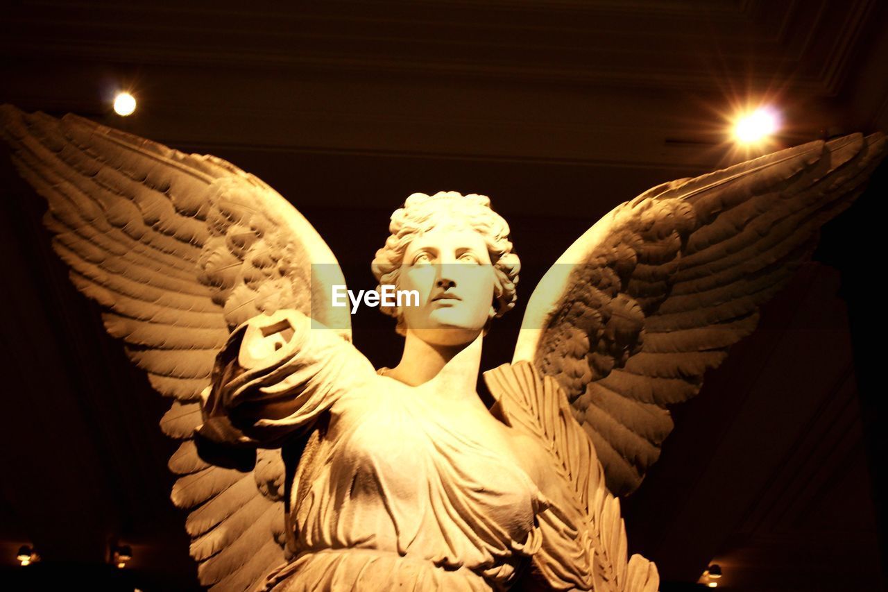 LOW ANGLE VIEW OF ANGEL STATUE AGAINST ILLUMINATED LIGHTS