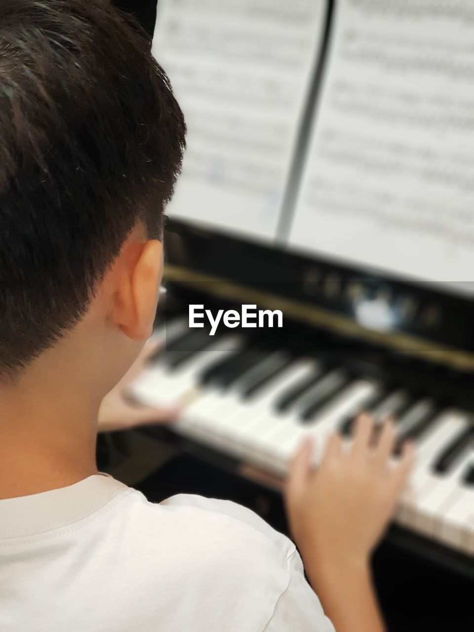 Rear view of boy playing piano