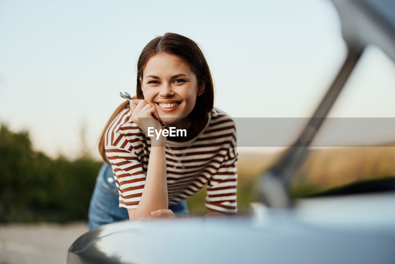 side view of young woman sitting on car