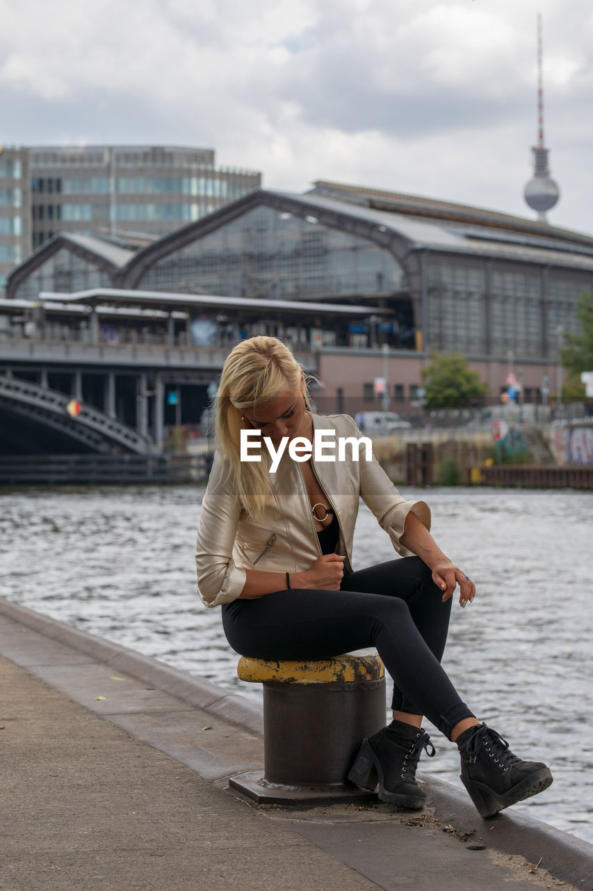 Rear view of woman sitting on bollard