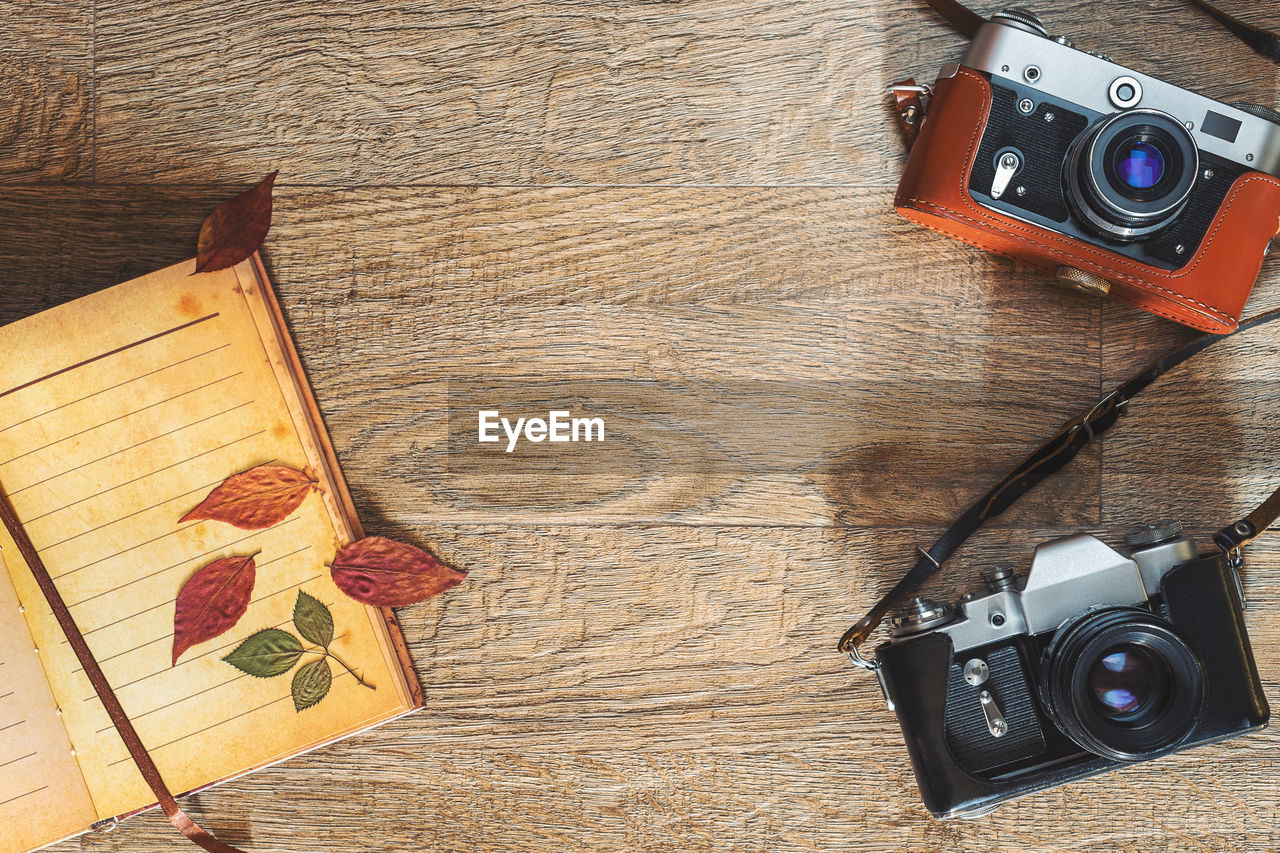 Old retro photo cameras in leather cases on wooden background. autumn composition with color  leaves