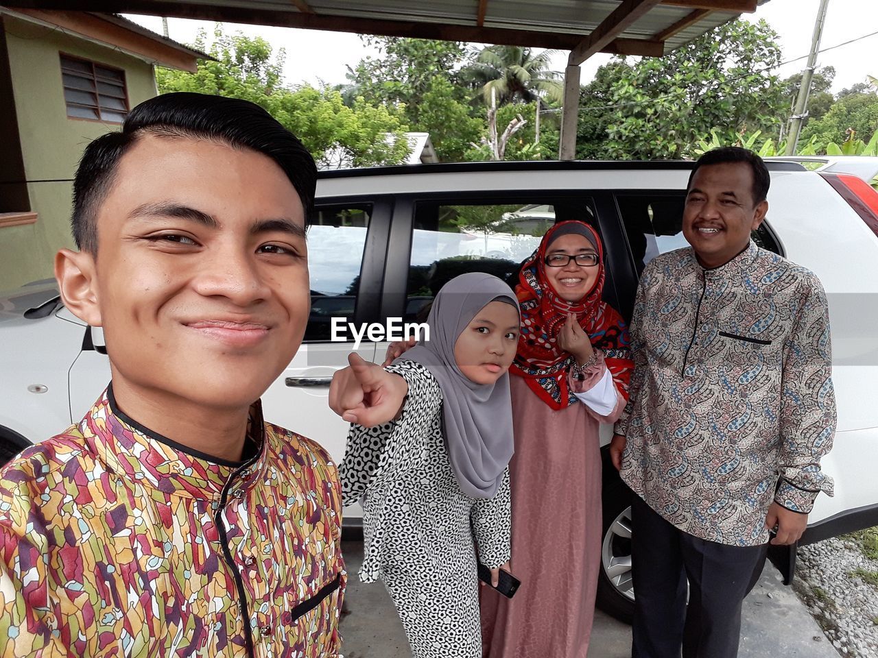 Portrait of smiling family standing against car