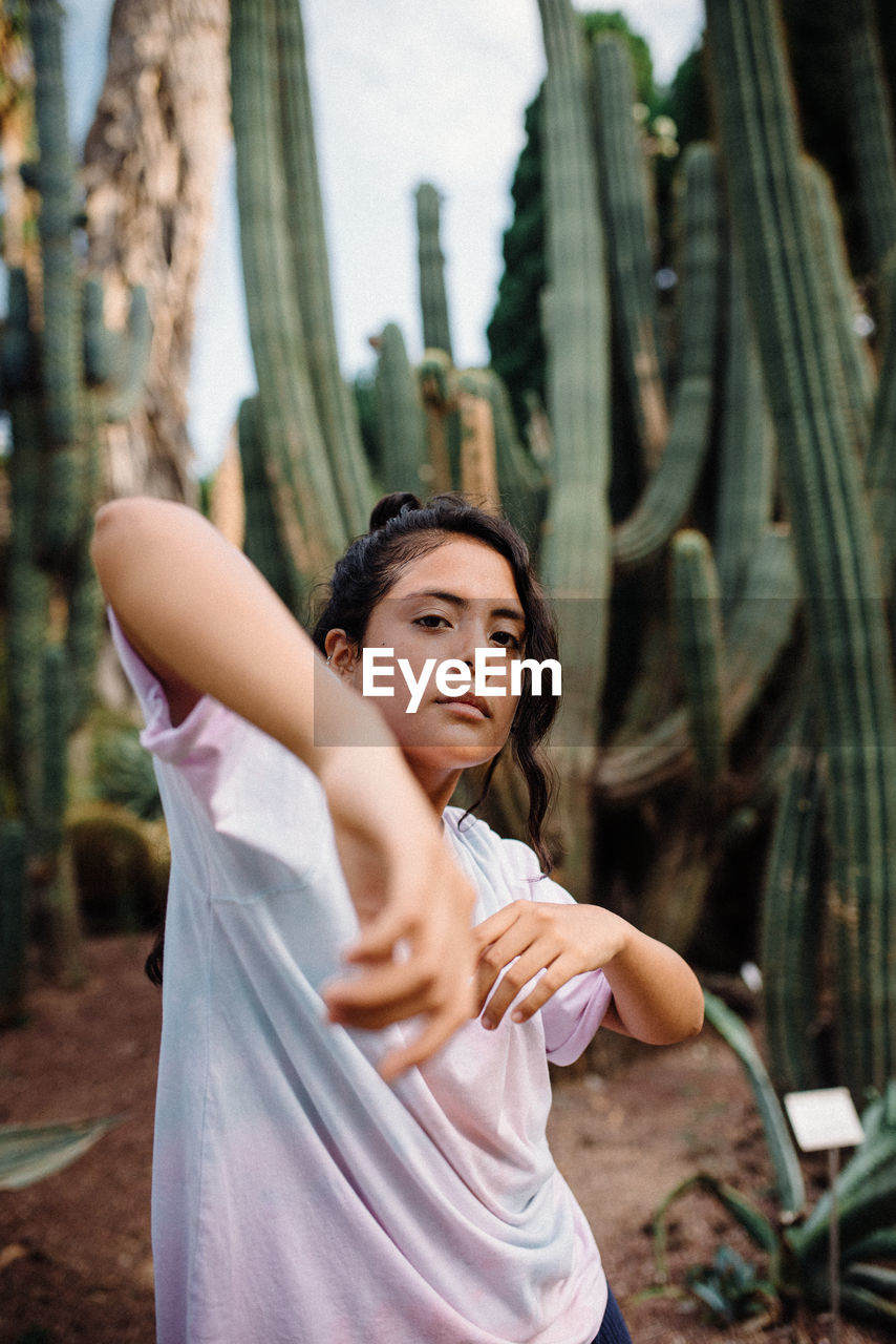 Latina girl with boho shirt dancing surrounded by cactus'