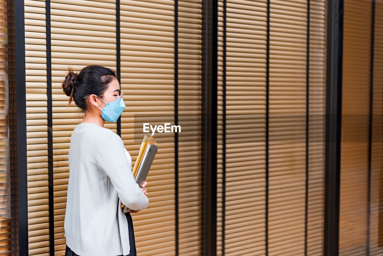 Side view of young woman looking through window